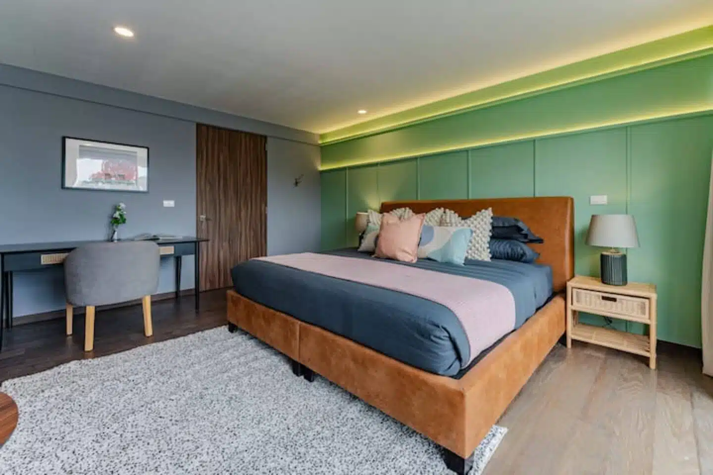 Mid-century style bedroom with a brown leather bed and a light green paneled wall with built-in led lighting.Villa Mexico City