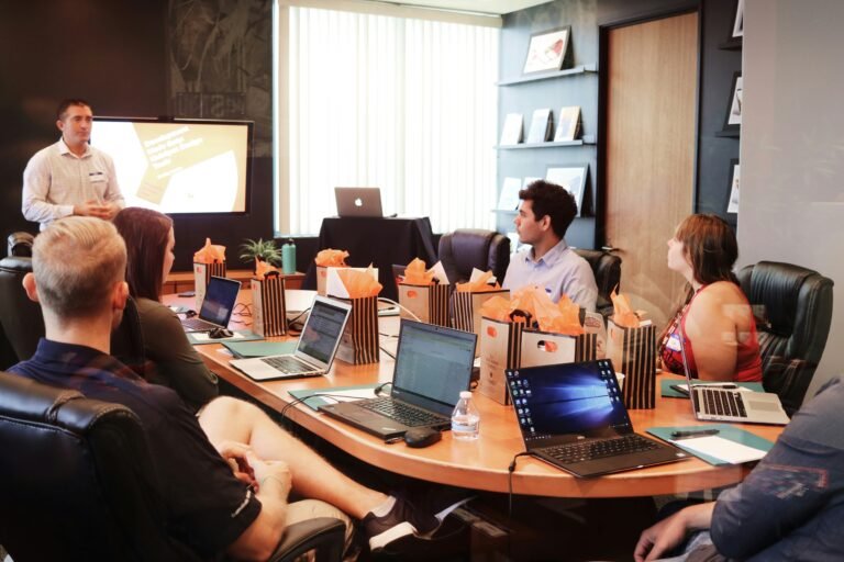 Professional team attending a business presentation in a modern boardroom with laptops and TV display at Two Travel Home.