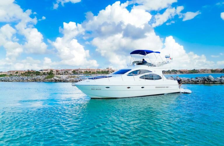 White modern motor yacht with blue bimini top cruising on bright turquoise Caribbean waters at Two Travel Home.