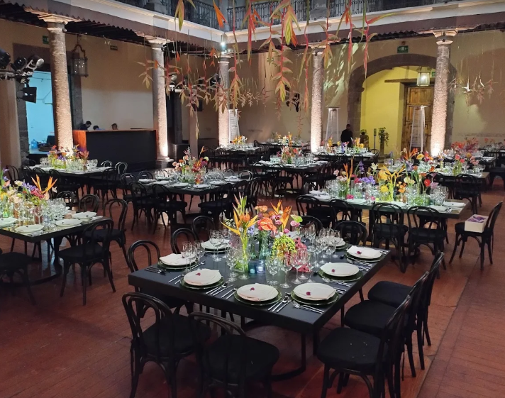 Upscale wedding reception banquet tables decorated with colorful floral centerpieces inside a colonial hall at Casa de la Bola Mexico City.