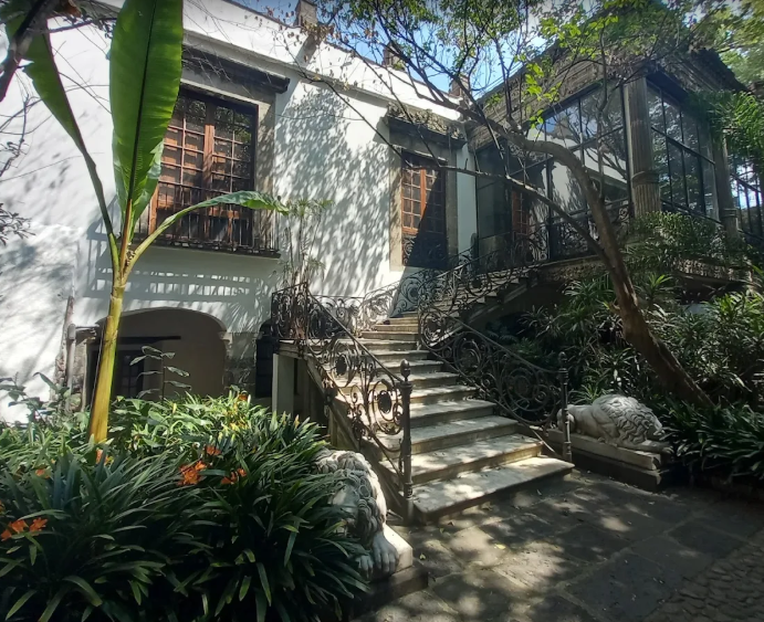 Elegant outdoor stone steps leading to a historic white colonial villa surrounded by palm trees at Casa de la Bola Mexico City.