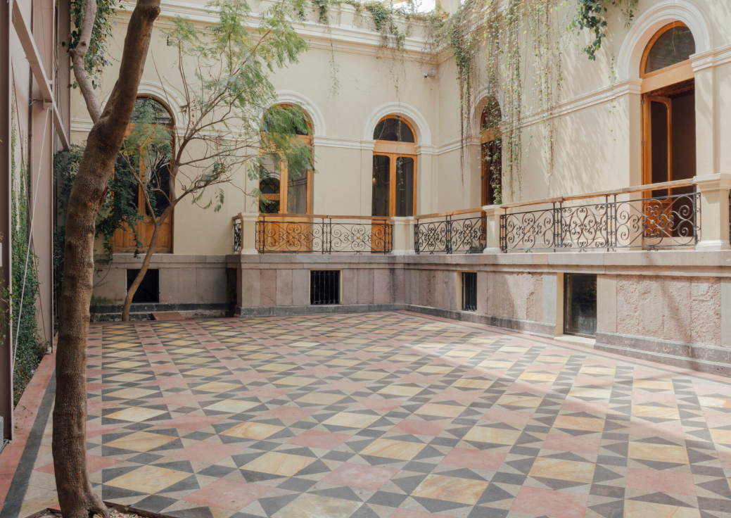 Wide view of the empty outdoor courtyard with mosaic tiles and stone balconies at Barcelona Mexico City.