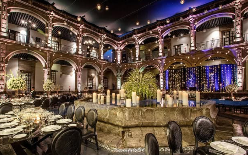 Classic colonial stone fountain decorated with thick candles and plants for a wedding reception at Ex Convento de San Hipolito Mexico City.