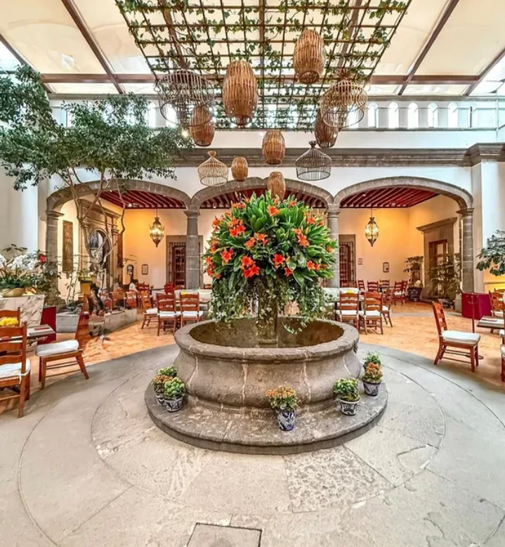 Wide view of a wedding reception setup in a courtyard with hanging wicker lanterns at Hacienda Los Morales Mexico City.