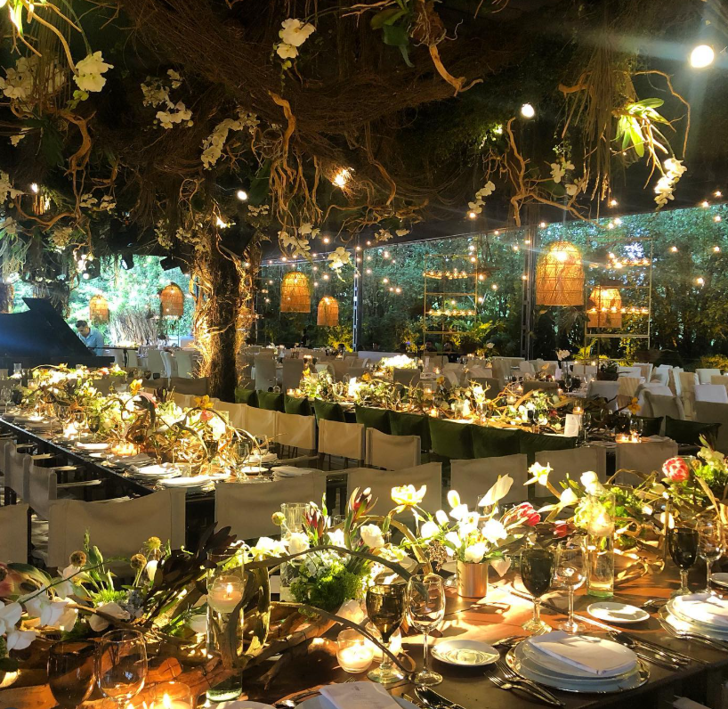 Romantic night wedding reception with long tables under a large tree decorated with woven basket lamps at Jardin Lomas Altas Mexico City.