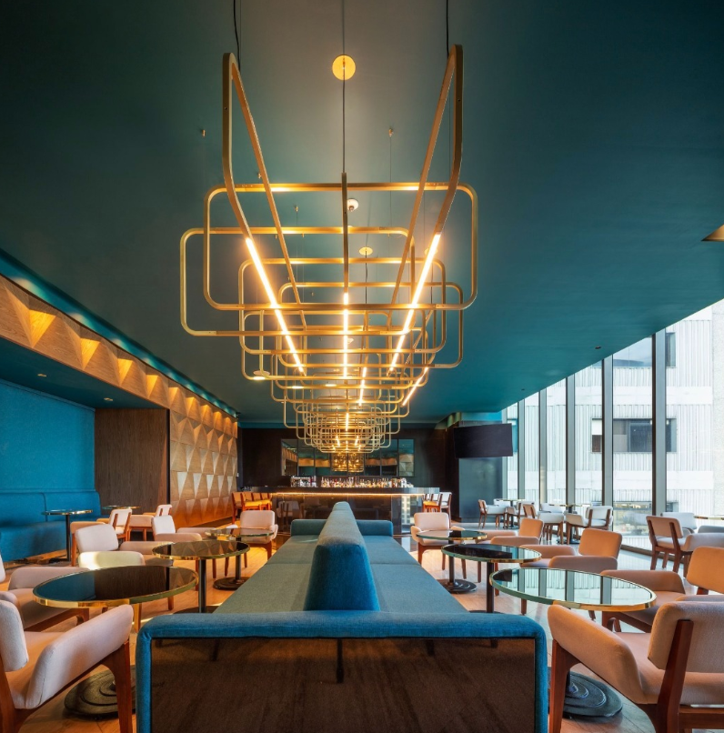 Sophisticated restaurant lounge with a teal ceiling and a large interlocking geometric brass chandelier at Sofitel Mexico City