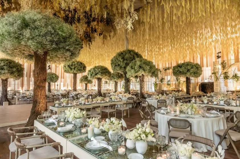 Extravagant wedding dinner setup with fake manicured trees and a yellow hanging flower ceiling at Jardin Santa Rita Mexico City.